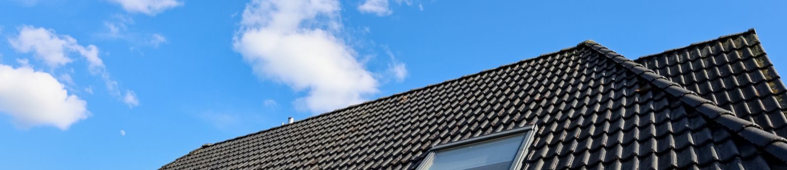 Pannendak van een woning onder een blauwe lucht