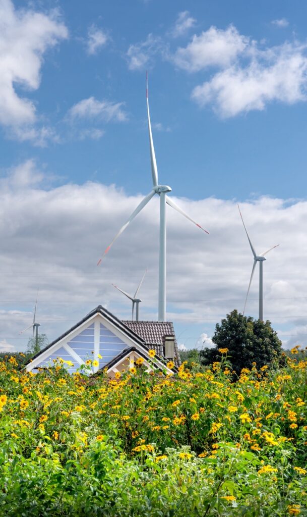 Energiezuinige woning tussen bloemen met windturbines op de achtergrond, duurzaam wonen