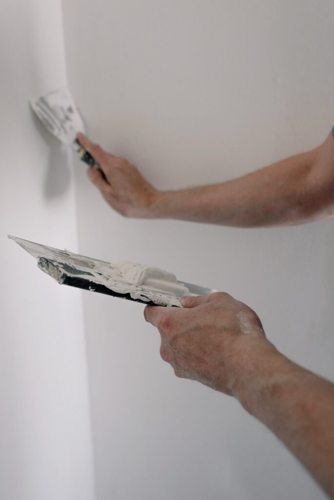 Stukadoor werkt een binnenmuur strak af met spaan en stucplaat