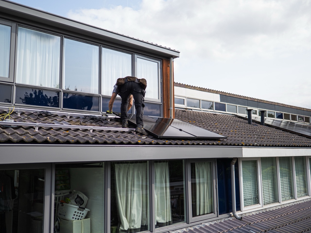 Installateur plaatst zonnepanelen op het dak van een woning voor verduurzaming